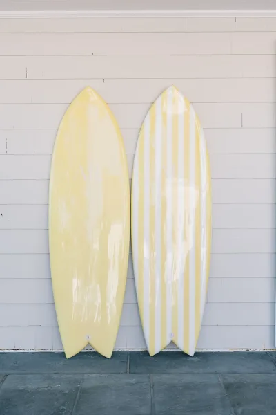Surfboard display styled as surfboard wedding decor, boards with monogram initials leaning against a white shiplap wall on a stone floor.