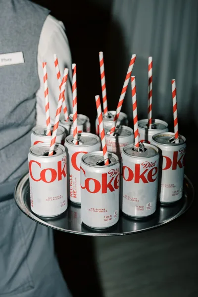 Passed drinks with mini soda cans on a tray carried by a server, ready for guests during the wedding cocktail hour