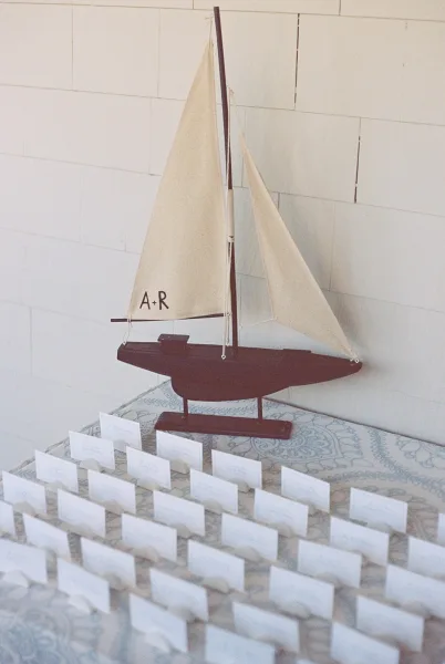Escort card display of nautical escort cards arranged in neat rows with sailboat decor atop a styled table, highlighting guest seating details.