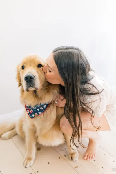 Bride with dog, kissing her golden retriever as they cuddle close in a sweet indoor getting-ready moment