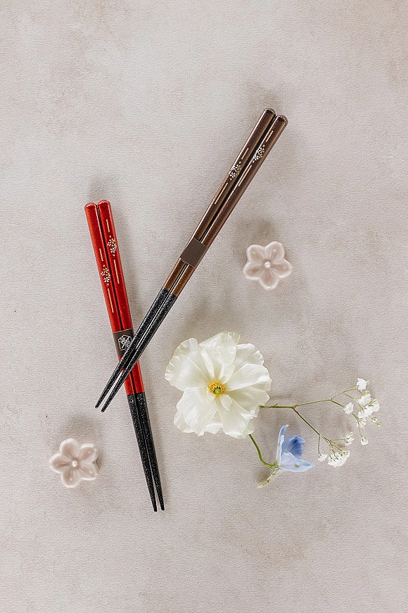 Wedding flat lay of wedding details flat lay with chopsticks and ceramic flower dishes, white and blue blooms and baby’s breath on light stone surface