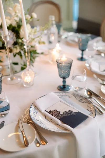 Wedding place setting in a blue and white table setting, highlighted by patterned china, arranged neatly for an elegant, timeless tablescape.