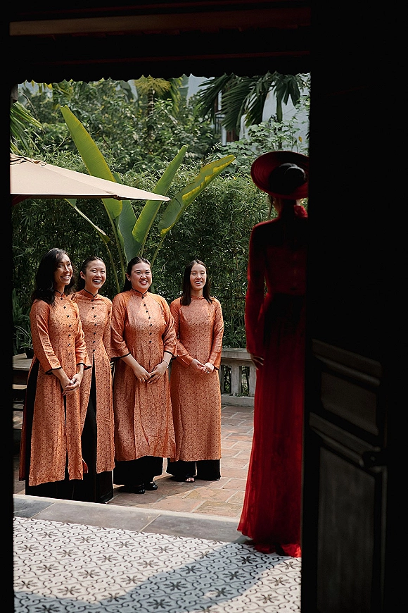 Bridesmaid reveal with matching bridesmaid dresses as they react on a tiled patio terrace, framed by doorway and tropical greenery