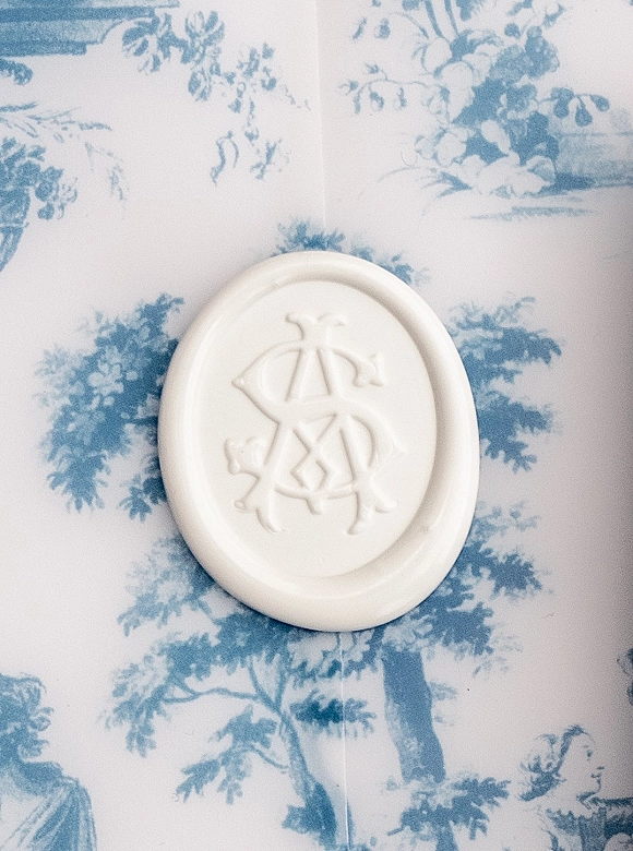 Wax seal with monogram wax seal detail in white, showing an embossed letterpress impression on blue and white toile patterned paper