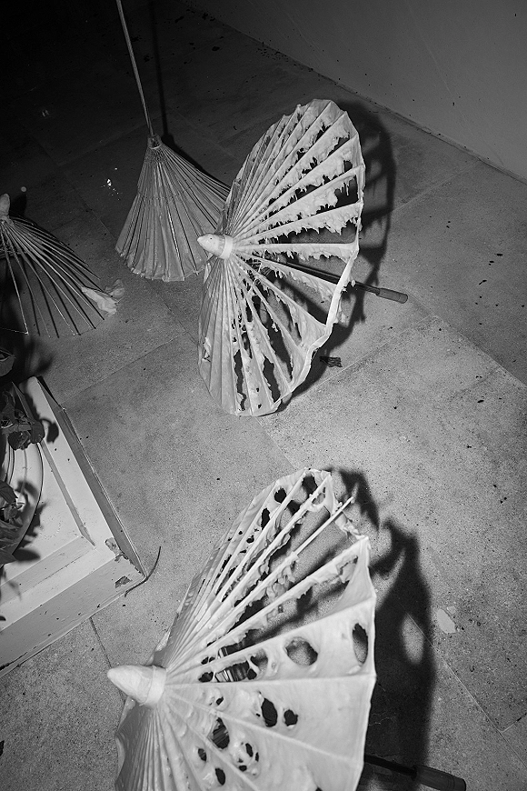 Wedding parasols with paper parasol wedding style, lace fabric and wooden handles arranged on stone steps beside leafy greenery