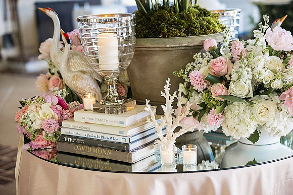 Wedding centerpiece decor with a wedding floral centerpiece of pink and white roses and hydrangea, moss base, pillar and votive candles on a mirrored table indoors