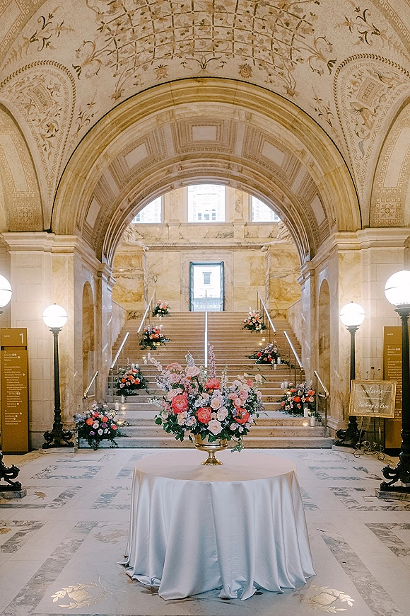 Wedding ceremony staircase with staircase wedding ceremony decor, lined with candles and floral arrangements in a marble hall under arched ceilings