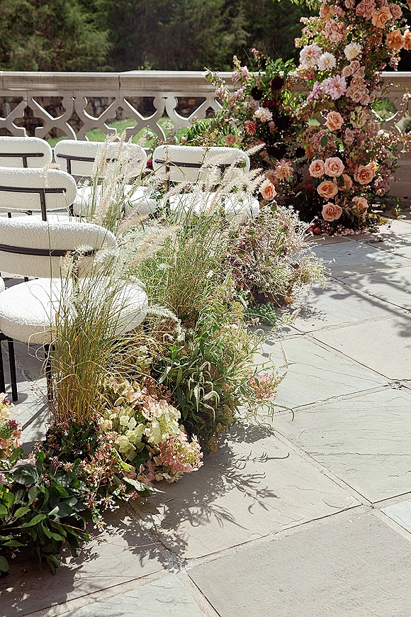 Ceremony aisle decor with grounded aisle florals in meadow clusters of garden roses, pampas grass and greenery on a stone terrace patio