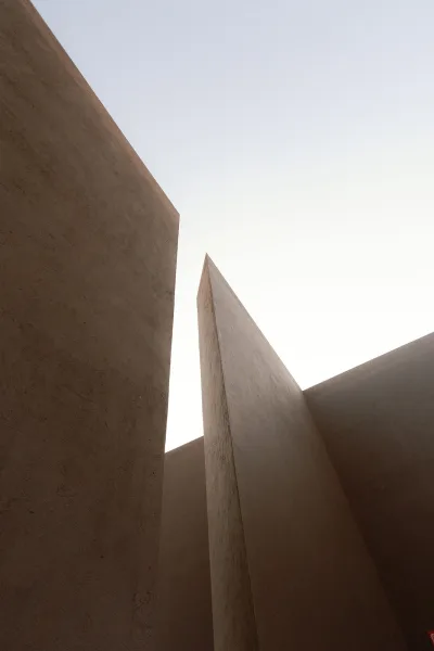 Architectural backdrop of modern architectural walls with minimalist concrete planes and clean lines against open sky, creating bold negative space