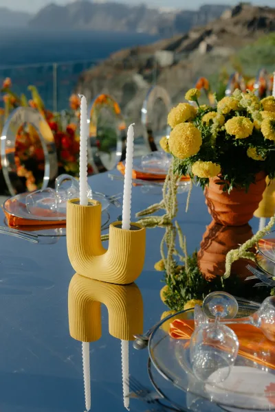 Reception tablescape in modern wedding table decor with a sculptural candle holder, overlooking ocean cliffs beyond a glass railing.