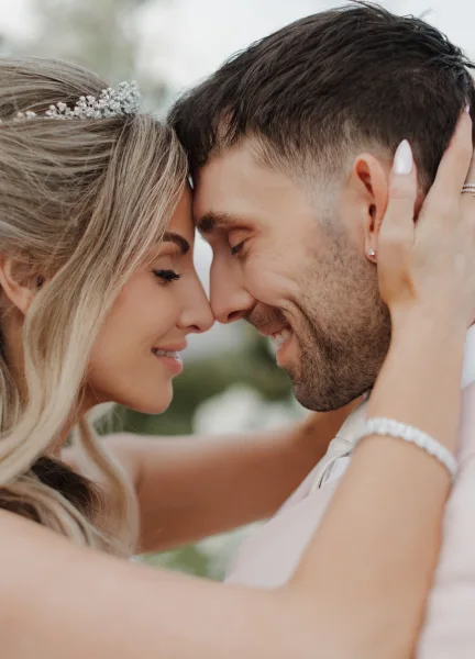 Couple portrait of newlyweds in a forehead touch pose, the bride’s engagement ring glinting as she holds his face, both smiling.
