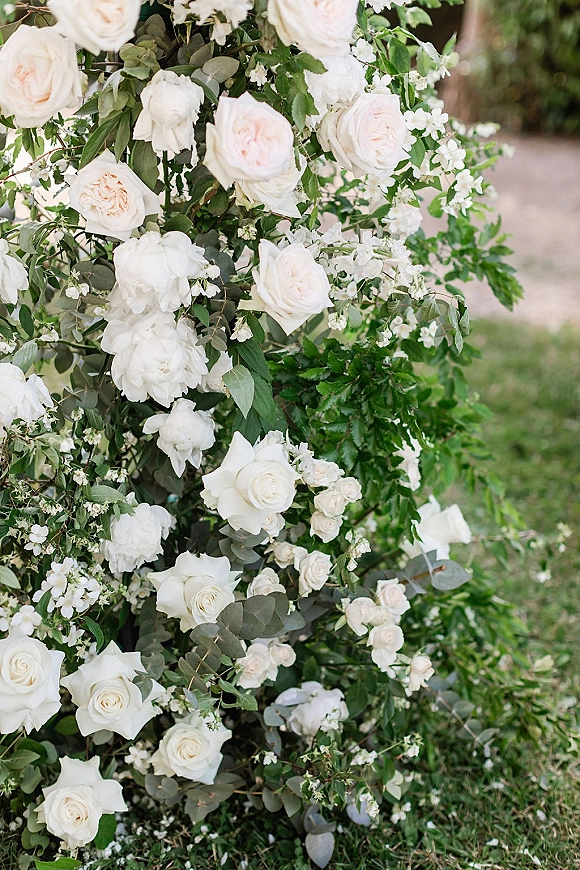 Wedding floral arrangement with a white rose arrangement of blush garden roses and eucalyptus on a grass lawn beside a garden path