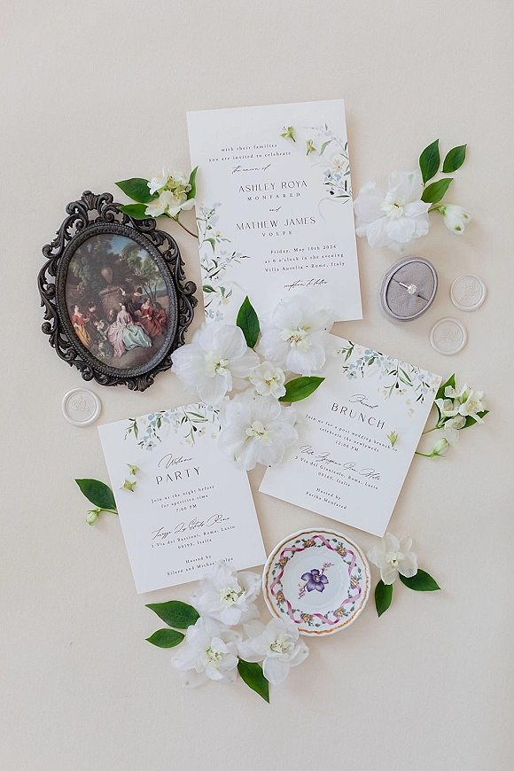 Wedding invitation suite with floral wedding invitations, wax seals, ring box and engagement ring, styled with white blooms on a neutral paper backdrop