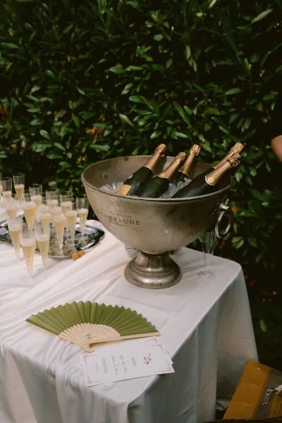 Champagne station serving cocktail hour champagne, with an ice bucket of chilled bubbly against garden greenery in an elegant outdoor setting.