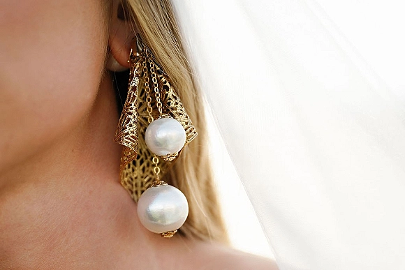 Bridal earrings with pearl drop earrings in gold filigree chandelier style, shown beside a bridal veil in soft light against blonde hair
