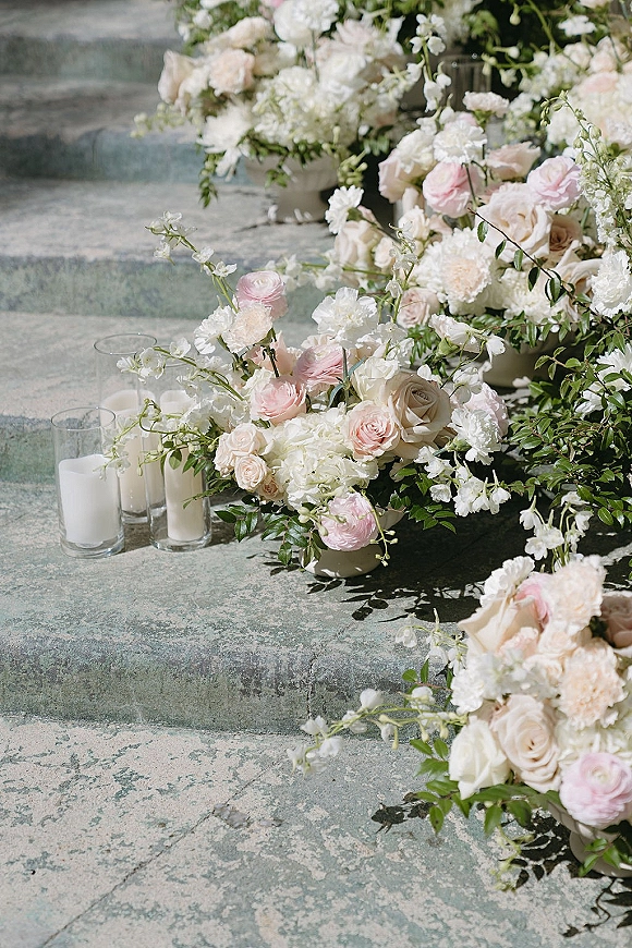 Ceremony aisle florals with wedding aisle flowers in blush and white, roses and greenery garland with glass cylinder candles on stone steps