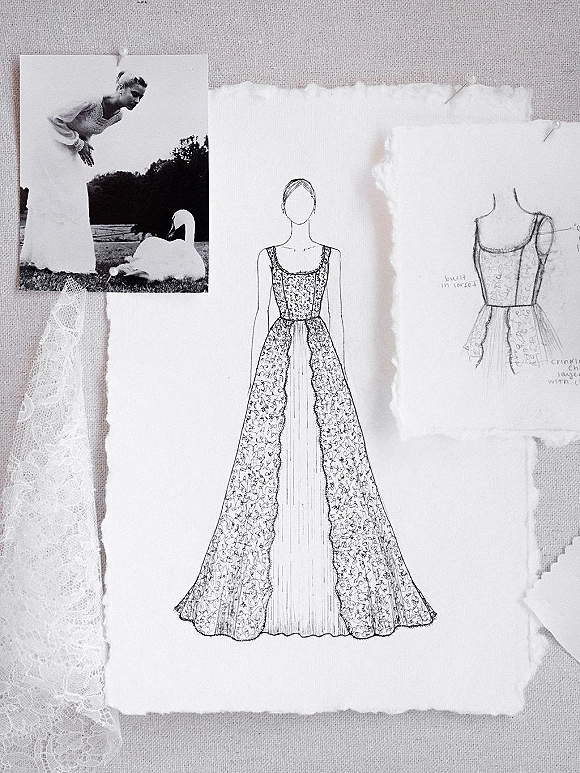 Wedding dress sketch pinned on torn paper with lace fabric swatch and black-and-white photo, styled on a linen surface