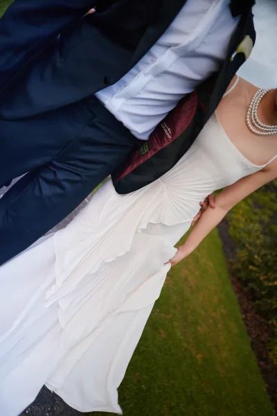Wedding dress detail highlighting a pleated wedding dress, its fitted bodice complemented by a pearl necklace for an elegant, modern look.