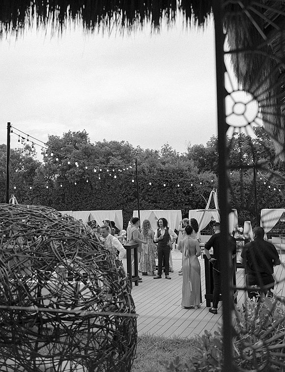 Wedding reception with outdoor wedding reception lounge seating under string lights, draped cabanas, cocktail tables, and lanterns on a patio lawn