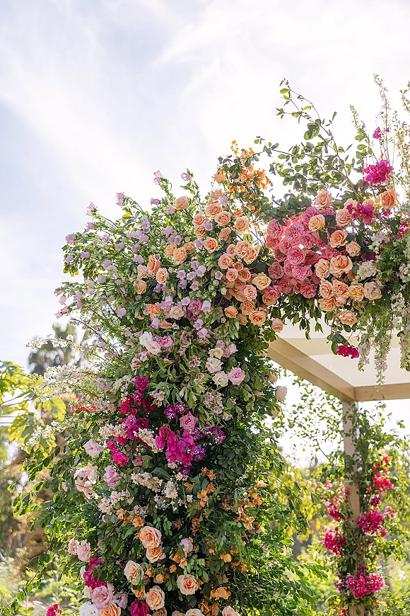 Floral ceremony arch with garden wedding arch blooms of roses, ranunculus and sweet peas on a pergola in an outdoor garden setting