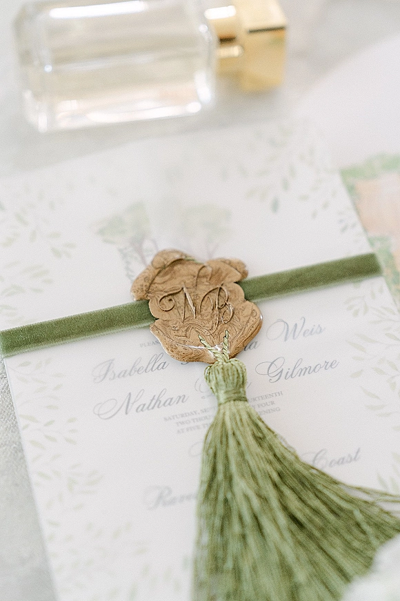 Wedding invitation suite with a wax seal wedding invitation, calligraphy on deckle edge paper tied with a green velvet ribbon on white surface