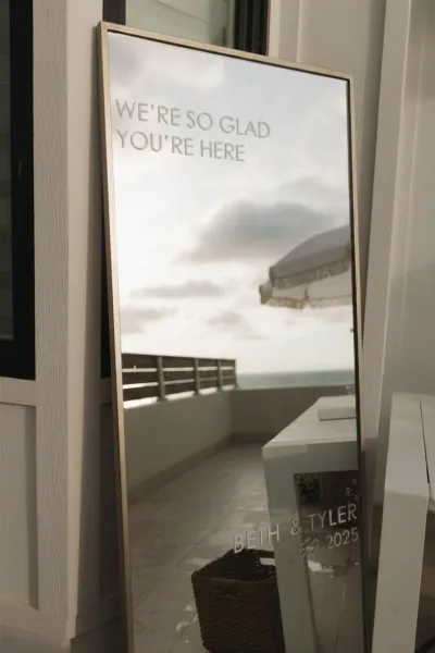 Wedding welcome sign as a mirror wedding sign on a patio overlooking the ocean, with sky and railing beside an umbrella and window