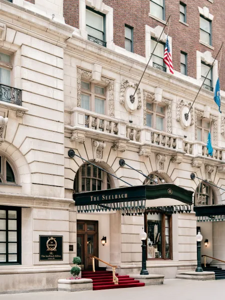 Hotel entrance with a wedding venue entrance marquee awning over red carpet steps, flags and lanterns on a historic stone facade with balcony