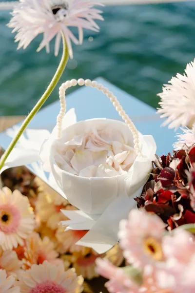 Flower girl basket as a sweet petal toss idea, detailed with a pearl handle and set by the water, ready for the aisle toss.