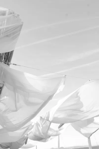 Fabric canopy decor with a sheer draped ceiling billowing above rigging cables against open sky and distant hills.