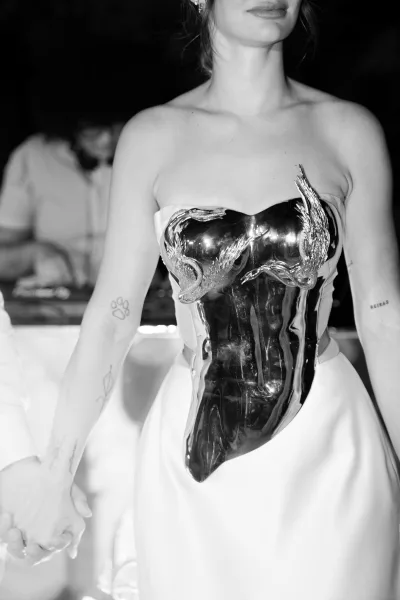 Wedding dress close-up featuring a metallic bodice dress and satin skirt, framed against a dark bar counter in an indoor setting.