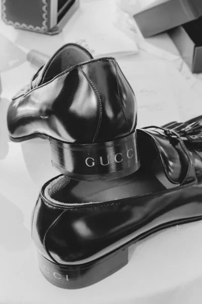 Groom shoes, black leather dress shoes with engraved soles arranged on a tabletop beside shoe boxes and a garment bag