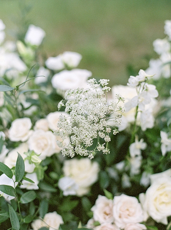 Wedding florals of white rose wedding flowers with Queen Anne's lace and lush greenery in a softly blurred garden backdrop