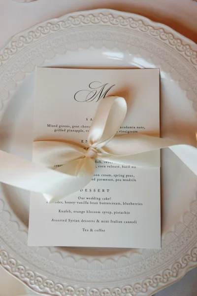 Wedding menu presented as a ribbon-tied menu card, set atop a charger plate for a polished, formal touch.