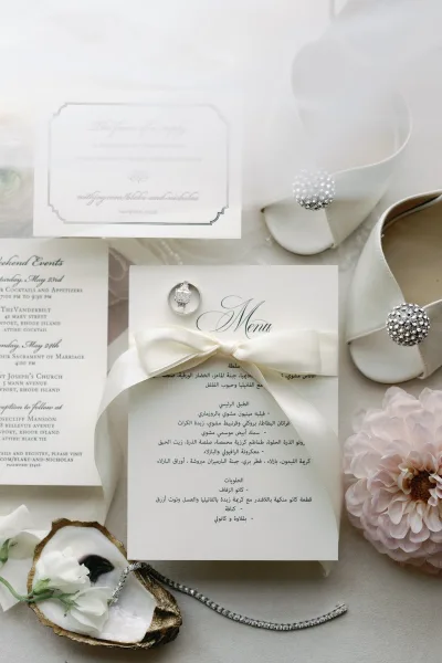 Invitation suite arranged as a wedding stationery flat lay, ivory and gray cards with classic typography beside an emerald-cut engagement ring.