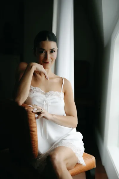 Bridal getting ready moment with a bride in satin slip, lace trim skimming her neckline as she takes a quiet breath before the ceremony.