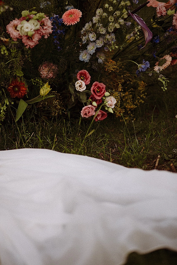 Wedding bouquet with wildflower wedding bouquet styling, purple calla lily and white delphinium, resting on grass with greenery
