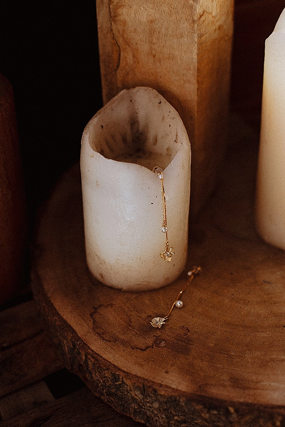 Wedding earrings with pearl drop earrings and gold drop setting on a wooden surface, softly lit by candlelight for a romantic detail flat lay