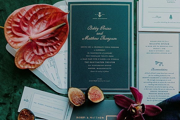 Invitation suite wedding invitation flat lay with navy and gold letterpress cards, map insert, figs and orchid on green fabric backdrop