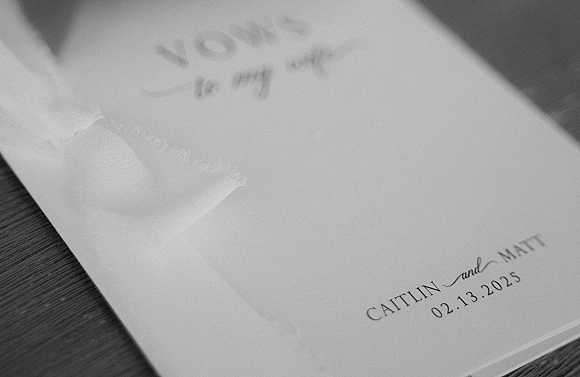 Wedding invitations arranged as an invitation suite on a wood table, featuring calligraphy lettering on deckled edge paper with vellum overlay