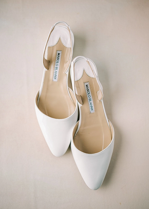 Bridal shoes in classic white wedding heels style, pointed-toe slingback pumps arranged on a neutral fabric surface flatlay