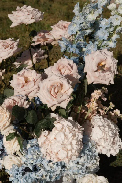 Wedding flower arrangement in blush and blue wedding flowers, featuring airy blue hydrangeas in a loose, garden-style design with soft movement.