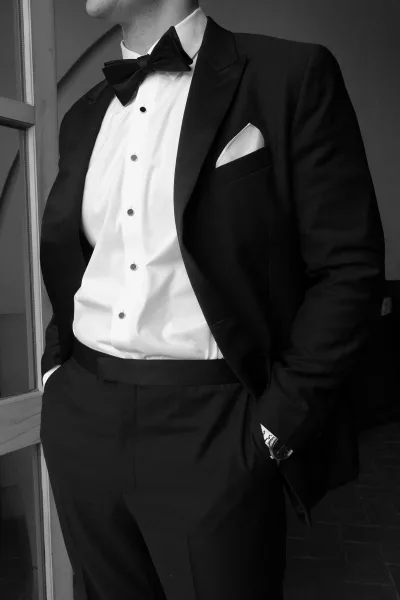Groom portrait in black tie groom style, wearing a tailored tuxedo with a classic bow tie and relaxed stance, confident and refined.