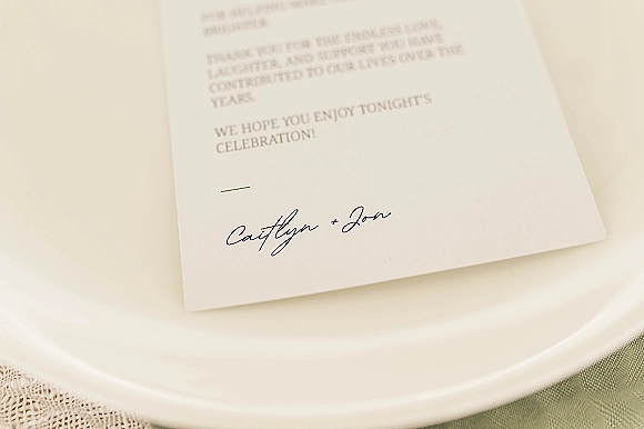 Wedding menu card with wedding menu wording in black script on white paper, set on a white plate with lace runner in soft light