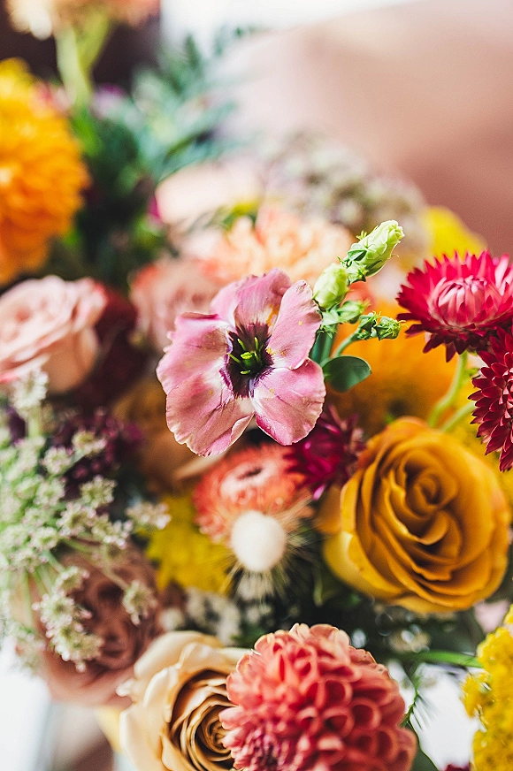 Wedding bouquet with colorful bridal bouquet blooms of roses and dahlias, layered with fresh greenery against a soft blurred background
