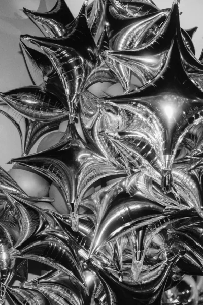 Wedding balloons with silver star balloons in a metallic foil cluster, strings hanging against an indoor wall backdrop