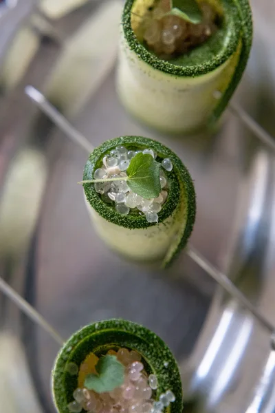 Cocktail hour drinks on a metal tray, featuring a wedding signature cocktail with green sugar rim, citrus twist, mint leaves, and skewers in soft bokeh