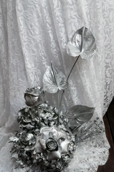 Bridal bouquet with silver wedding bouquet florals—painted roses, hydrangea and anthurium stems with lace fabric on a white lace backdrop