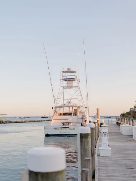 Wedding boat portrait of a bride and groom on a yacht by dock pilings, with ocean water and a marina horizon behind them