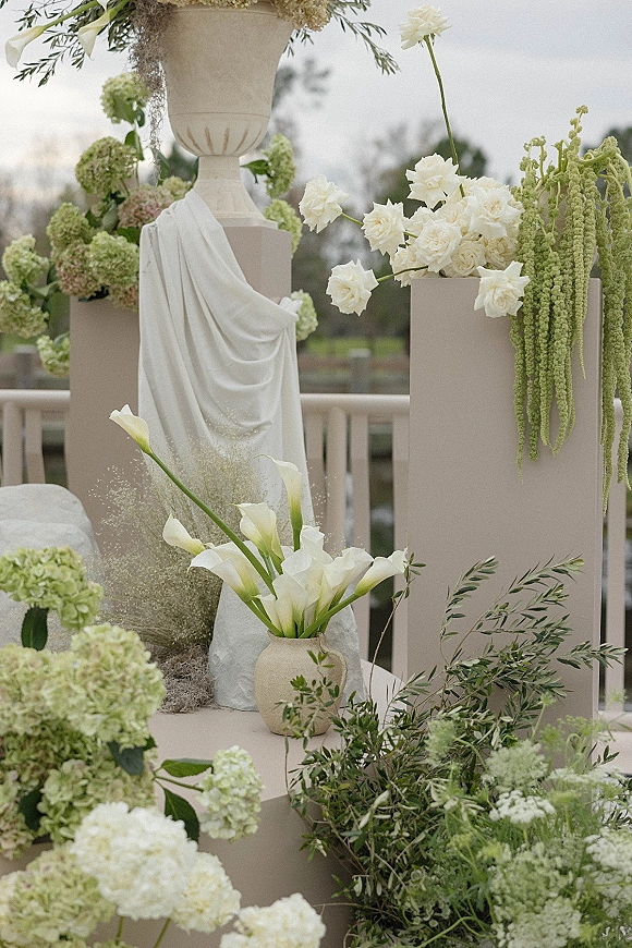 Wedding ceremony decor with wedding altar flowers on pedestal plinths, featuring hydrangeas, calla lilies, and draped fabric on a terrace