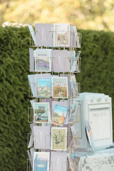 Postcard guestbook, a wedding guestbook alternative, displayed with a card rack against a garden hedge and greenery.